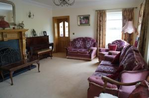 a living room with purple furniture and a piano at Kilcreeny Lodge in Lisburn