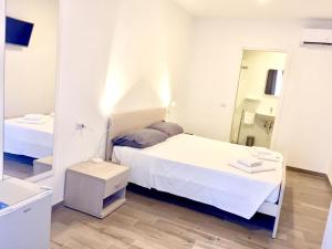 Habitación blanca con cama y espejo en Academy Hotel en Fiumicino