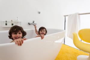 2 bambini che giocano in una vasca da bagno in bagno di Maison Du Collectionneur ad Aix en Provence