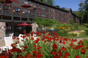 a garden with red flowers in front of a building at Station Touristique Duchesnay - Sepaq in Sainte-Catherine
