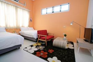 1 dormitorio con 2 camas, silla roja y TV en Time Travel B&B en Taitung