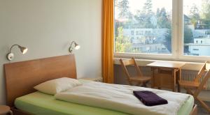 a bedroom with a bed and a table and a window at Hostel 77 Bern in Bern
