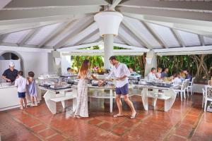 a man and a woman standing at tables in a restaurant at Forte Village Resort - Villa Del Parco & Spa in Santa Margherita di Pula
