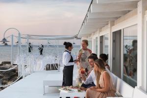 a group of people sitting around a table on a balcony at La Peschiera in Monopoli