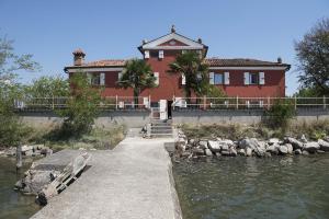 una grande casa rossa accanto a un corpo d'acqua di Panigai House a Aquiléia