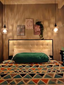 a bedroom with a green bed with two pendant lights at Shofiya Guesthouse Solo in Solo