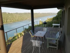 einen Balkon mit einem Tisch und Stühlen sowie Flussblick in der Unterkunft River Cottage in Kenton on Sea