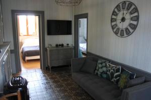 a living room with a couch and a clock on the wall at Cosy Cottage in Beugin