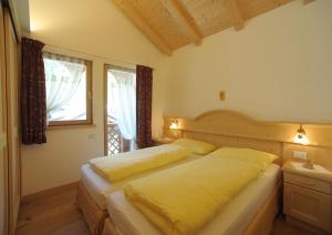 a bedroom with a bed with yellow sheets and a window at Romantic Chalet Dolomiti in Val di Zoldo