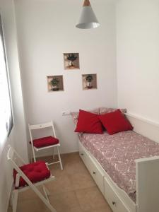 een slaapkamer met een bed met rode kussens en een stoel bij Apartamento Infantes in Ronda