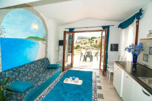 een woonkamer met een blauwe bank en een keuken bij Sant'Anna Charming Apartments in Budoni