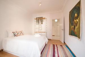 リスボンにあるArt and Design Apartment in Lisbonの白いベッドと壁に絵画が飾られたベッドルーム1室