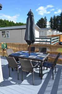 a table and chairs with an umbrella on a patio at The Balmoral Caravan in Dornoch