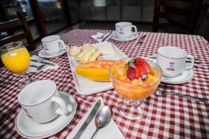 a table with a bowl of fruit and a plate of food at Assay Plaza Hotel in Hortolândia