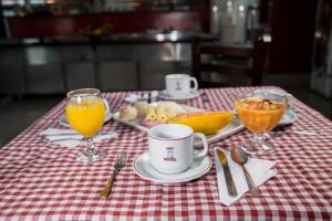a table with a red and white checkered table cloth with orange juice at Assay Plaza Hotel in Hortolândia +54 photos