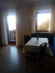 een eetkamer met een tafel en twee ramen bij Steinerhof in Dobbiaco