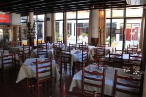 un comedor con mesas, sillas y ventanas en Hotel O Gato - Edificio Standard, en Odivelas