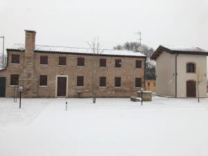 een groot bakstenen gebouw in de sneeuw naast een gebouw bij Casa Sansovino in Pontecasale