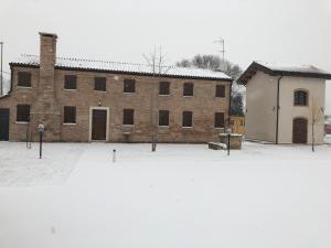 ein großes Backsteingebäude mit Schnee auf dem Boden in der Unterkunft Casa Sansovino in Pontecasale