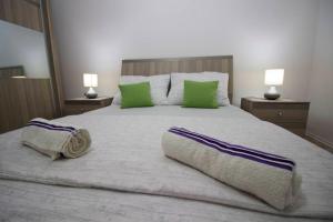 a large white bed with green pillows on it at Apartment Garden in Blagaj