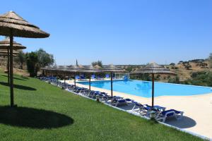 a pool at a resort with chairs and umbrellas at Hotel O Gato - Edificio Standard in Odivelas