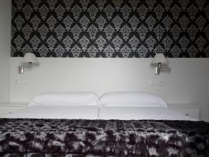 a bedroom with a bed with a black and white wallpaper at Apartamentos Turisticos Estrella del Alemar in Langre