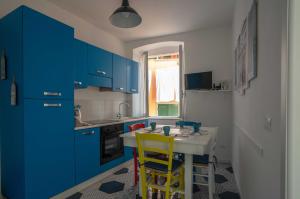 a kitchen with blue cabinets and a table with yellow stools at Oceano d'Amore in Riomaggiore
