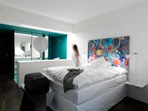 1 dormitorio con 1 cama blanca y una pintura en la pared en City Garden Hotel en Zug