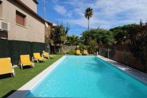 a swimming pool with yellow chairs next to a house at Pool and relax 20' from Barcelona in Premiá de Mar