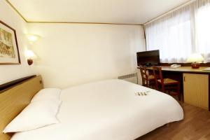 デンボスにあるカンパニール ホテル & レストランズ スヘルトーヘンボスの白いベッドとデスクが備わるホテルルームです。