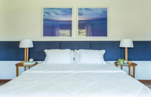 a bedroom with a large white bed with two windows at Haute Haus - Guest House in Florianópolis