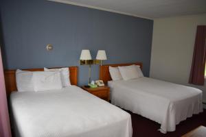 een hotelkamer met 2 bedden met witte lakens bij Country Club Motel in Old Forge