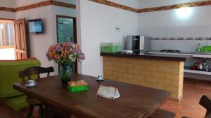 uma cozinha com uma mesa de madeira com um vaso de flores em Apartahotel La Gran Familia em Villa de Leyva