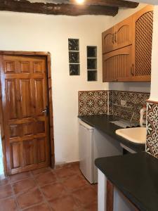 cocina con puerta de madera y fregadero en CASA M'GUIRE, en Pampaneira