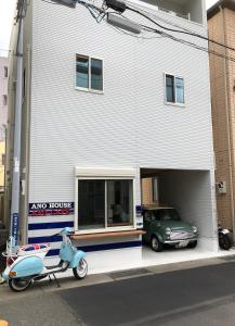 a scooter parked in front of a building with a car at Ano House Guesthouse(Female Only) in Kamakura