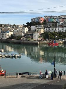 a group of people walking on a sidewalk near a river at Mariners Cottage - Wake Up to Uninterrupted Sea Views in Brixham