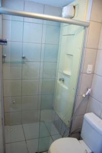 uma casa de banho com uma cabina de duche em vidro e um WC. em Terrazzo Praia Flat em Natal