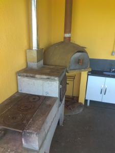 a kitchen with an old stove in a yellow wall at Chácara Áquila in São Roque