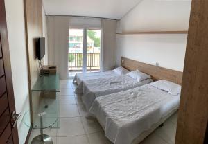 a bedroom with two beds and a glass table at Apartamento no Club Meridional in Praia dos Carneiros