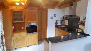 cocina con armarios de madera y encimera negra en Farfalla en Gstaad