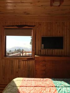 1 dormitorio con cama, ventana y TV en Cabañas Quillay, en Constitución