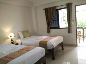 um quarto de hotel com duas camas e uma janela em Rena House Chiang Mai em Chiang Mai