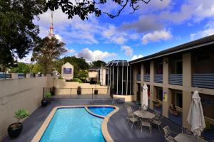 a swimming pool with tables and chairs next to a building at Twin Towers Inn in Sydney