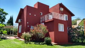 a red house with flowers in front of it at Cabañas Luna del Sur in Merlo