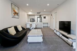 a living room with a black couch and a tv at Spice Apartments by CLLIX in Brisbane