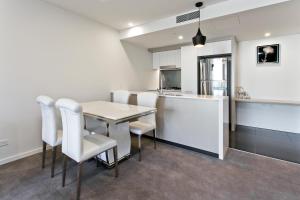 a kitchen with a table, chairs and a refrigerator at Spice Apartments in Brisbane