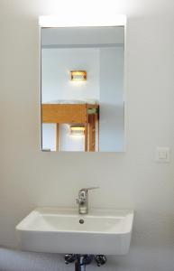 lavabo en el baño con un espejo grande encima. en Hostel 77 Bern en Berna