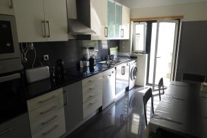 uma cozinha com armários brancos, um lavatório e um fogão em Partilha Sol Apartment em Alvor