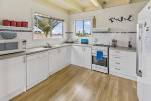 a white kitchen with white appliances and a wooden floor at Tanjil in Paynesville