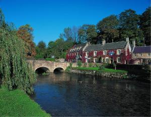 a bridge over a river in a village with houses at The Swan Hotel in Bibury